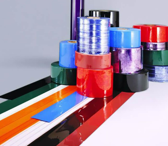 Stacks of colorful adhesive tape rolls and long strips are laid flat on a white surface, much like materials used for strip curtain doors Tecumseh, showcasing vibrant hues including red, blue, black, white, green, and orange.